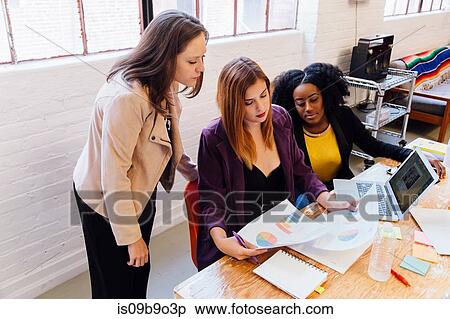 Colleagues in office discussing graphical data on paperwork View Large Photo Image Stock Photography - Colleagues in office discussing graphical data on paperwork. Fotosearch