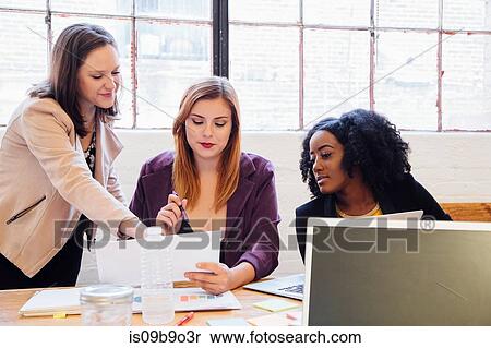 Stock Photography - Colleagues in office discussing paperwork. Fotosearch