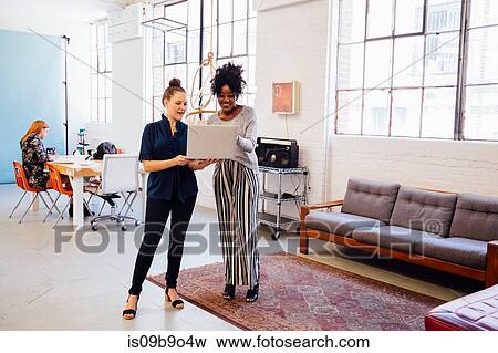 Stock Photo - Colleagues in office using laptop together. Fotosearch