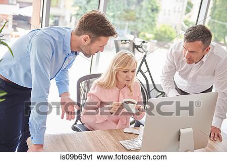 Colleagues in office with computer having discussion View Large Photo Image Stock Photograph - Colleagues in office with computer having discussion. Fotosearch