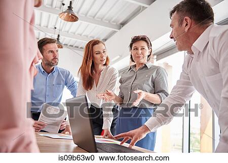 Colleagues in office with laptop having discussion View Large Photo Image Stock Image - Colleagues in office with laptop having discussion. Fotosearch
