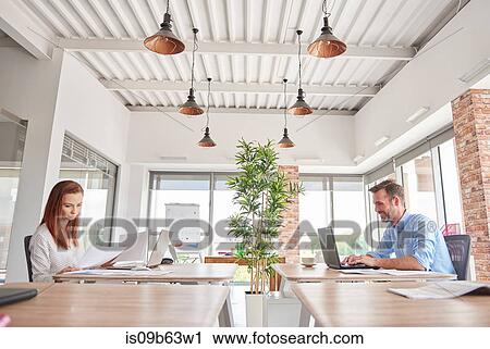 Colleagues in office working at desks View Large Photo Image Stock Image - Colleagues in office working at desks. Fotosearch