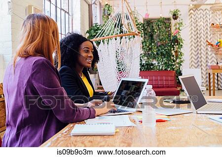 Picture - Colleagues working together at desk, using laptop. Fotosearch