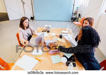 Colleagues working together at desk sharing doughnuts View Large Photo Image Stock Photo - Colleagues working together at desk sharing doughnuts. Fotosearch