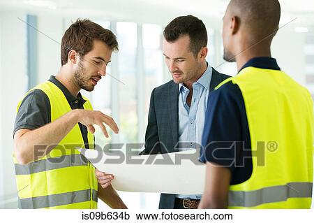 Stock Image - Construction workers and businessman, looking at plans. Fotosearch