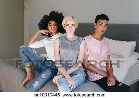 Cool mid adult man and two female friends sitting on bed, portrait View Large Photo Image Stock Photography - Cool mid adult man and two female friends sitting on bed, portrait. Fotosearch