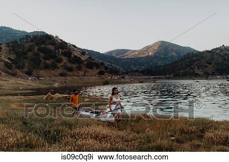 Stock Image - Couple carrying kayak by lake, Kaweah, California, United States. Fotosearch