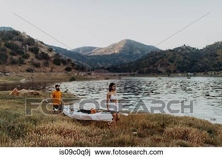 Stock Image - Couple carrying kayak by lake, Kaweah, California, United States. Fotosearch