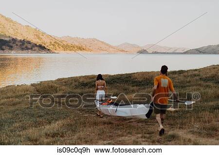 Stock Image - Couple carrying kayak to lake, Kaweah, California, United States. Fotosearch