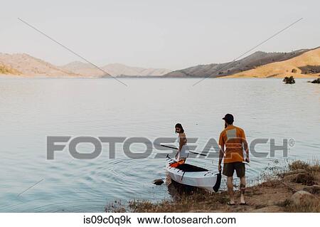 Stock Image - Couple carrying kayak to lake, Kaweah, California, United States. Fotosearch