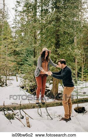 Stock Image - Couple crossing over fallen tree trunk in forest, Tobermory, Canada. Fotosearch
