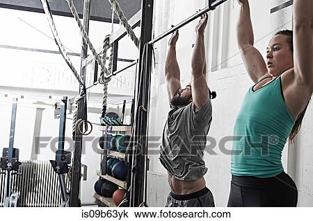Couple doing chin-up in cross training gym View Large Photo Image Stock Image - Couple doing chin-up in cross training gym. Fotosearch