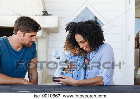 Couple e-learning with daughter on smartphone in beach house View Large Photo Image Stock Photo - Couple e-learning with daughter on smartphone in beach house. Fotosearch