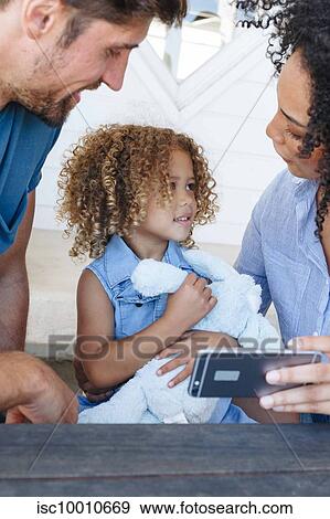 Couple e-learning with daughter on smartphone in beach house View Large Photo Image Stock Photo - Couple e-learning with daughter on smartphone in beach house. Fotosearch