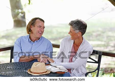 Couple enjoying conversation under shade in garden View Large Photo Image Stock Image - Couple enjoying conversation under shade in garden. Fotosearch