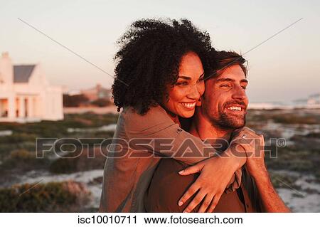 Couple enjoying view of sunset on beach View Large Photo Image Stock Image - Couple enjoying view of sunset on beach. Fotosearch