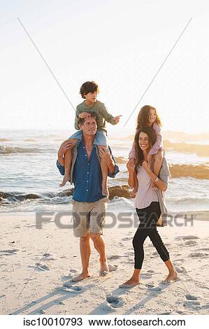 Couple giving children piggyback ride on beach View Large Photo Image Stock Image - Couple giving children piggyback ride on beach. Fotosearch