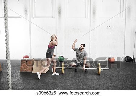 Stock Photograph - Couple giving high five in cross training gym. Fotosearch