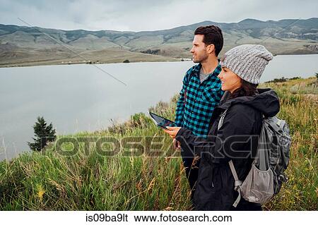 Couple hiking, standing beside Dillon Reservoir, young woman holding digital tablet, Silverthorne, Colorado, USA View Large Photo Image Stock Photograph - Couple hiking, standing beside Dillon Reservoir, young woman holding digital tablet, Silverthorne, Colorado, USA. Fotosearch