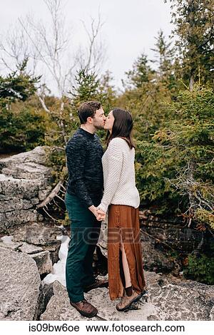 Stock Image - Couple holding hands and kissing, Tobermory, Canada. Fotosearch