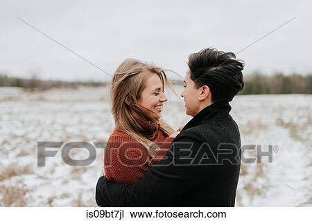 Stock Image - Couple hugging in snowy landscape, Georgetown, Canada. Fotosearch