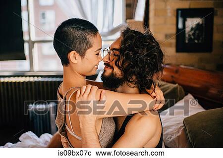 Stock Image - Couple hugging sitting on bed. Fotosearch