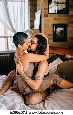 Stock Image - Couple hugging sitting on bed. Fotosearch