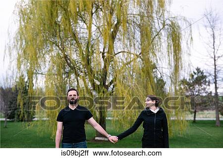 Stock Image - Couple in front of willow tree in park, Kingston, Canada. Fotosearch