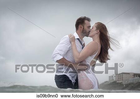 Stock Image - Couple in sea kissing. Fotosearch