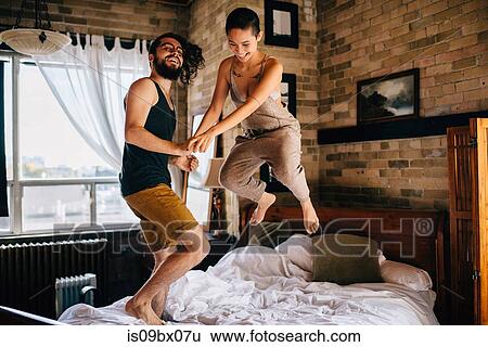 Couple jumping on bed View Large Photo Image Stock Photograph - Couple jumping on bed. Fotosearch