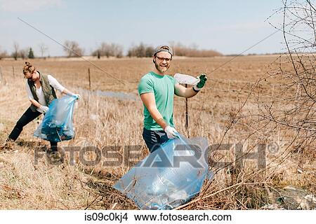Couple picking up rubbish by field, Georgetown, Canada View Large Photo Image Picture - Couple picking up rubbish by field, Georgetown, Canada. Fotosearch