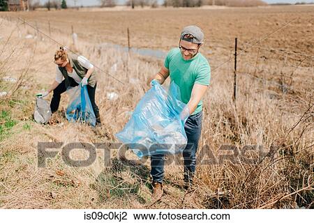 Couple picking up rubbish by field, Georgetown, Canada View Large Photo Image Stock Image - Couple picking up rubbish by field, Georgetown, Canada. Fotosearch