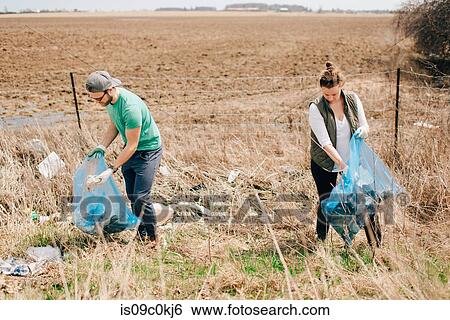 Stock Photograph - Couple picking up rubbish by field, Georgetown, Canada. Fotosearch