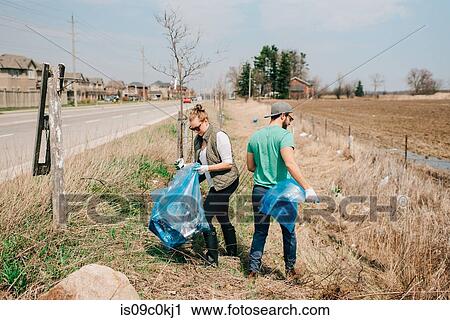Stock Image - Couple picking up rubbish by roadside, Georgetown, Canada. Fotosearch