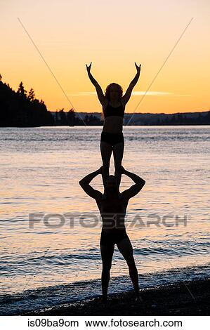 Couple practising yoga on beach at sunset View Large Photo Image Picture - Couple practising yoga on beach at sunset. Fotosearch