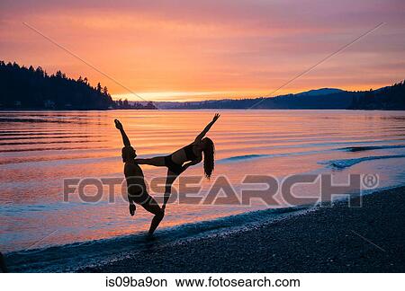 Couple practising yoga on beach at sunset View Large Photo Image Picture - Couple practising yoga on beach at sunset. Fotosearch
