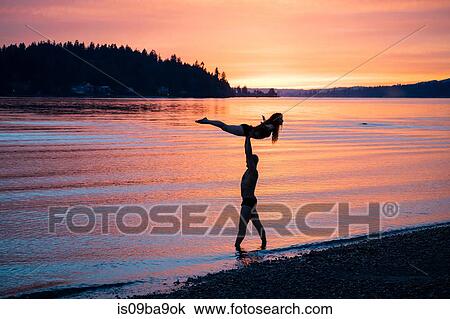 Couple practising yoga on beach at sunset View Large Photo Image Stock Image - Couple practising yoga on beach at sunset. Fotosearch