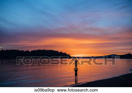 Stock Photography - Couple practising yoga on beach at sunset. Fotosearch
