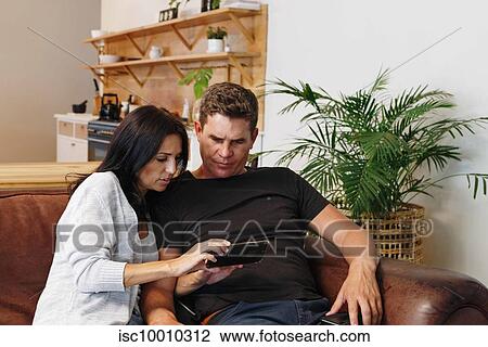 Stock Image - Couple reading text message on mobile phone at home. Fotosearch