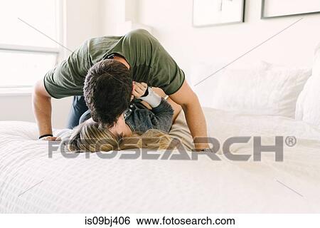 Couple relaxing on bed, kissing View Large Photo Image Stock Photograph - Couple relaxing on bed, kissing. Fotosearch