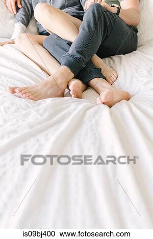 Couple relaxing on bed, legs entwined, cropped View Large Photo Image Stock Image - Couple relaxing on bed, legs entwined, cropped. Fotosearch