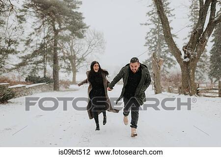 Stock Image - Couple running in snowy landscape, Georgetown, Canada. Fotosearch