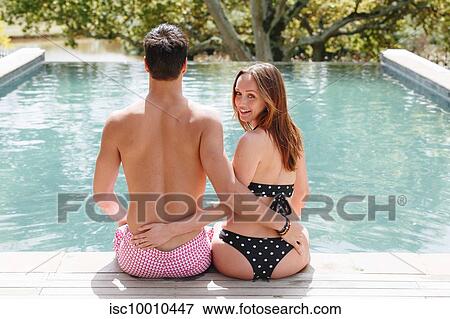 Stock Photo - Couple sitting by swimming pool. Fotosearch
