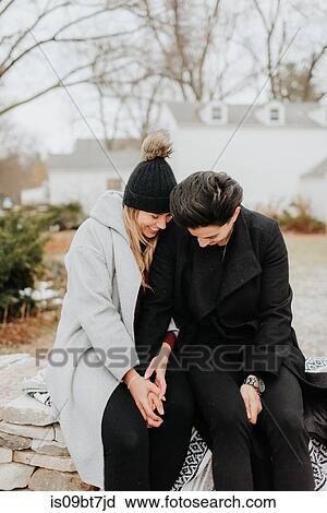 Stock Image - Couple sitting on blanket on low wall. Fotosearch