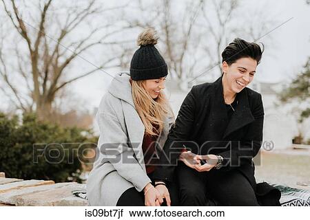 Stock Image - Couple sitting on blanket on low wall. Fotosearch