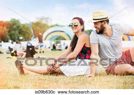 Couple sitting on grass together at festival View Large Photo Image Stock Image - Couple sitting on grass together at festival. Fotosearch