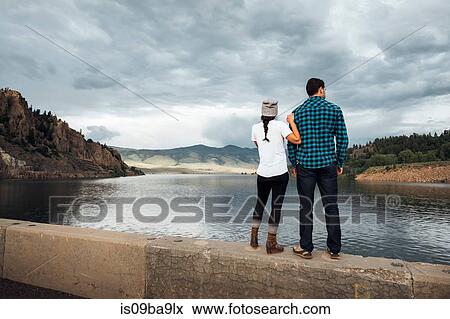Stock Photo - Couple standing on wall beside Dillon Reservoir, looking at view, rear view, Silverthorne, Colorado, USA. Fotosearch
