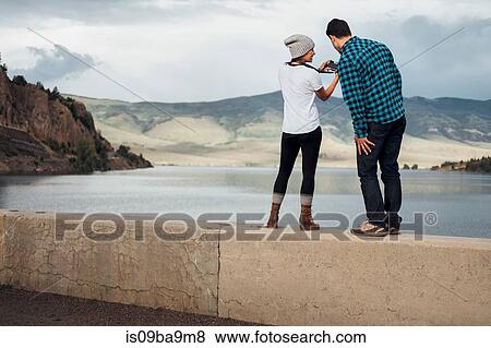 Stock Photo - Couple standing on wall beside Dillon Reservoir, looking at camera, rear view, Silverthorne, Colorado, USA. Fotosearch