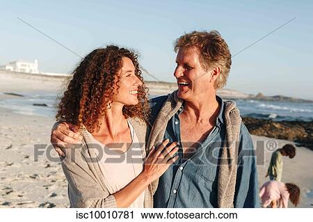 Couple taking walk on sandy beach, children in background View Large Photo Image Stock Image - Couple taking walk on sandy beach, children in background. Fotosearch