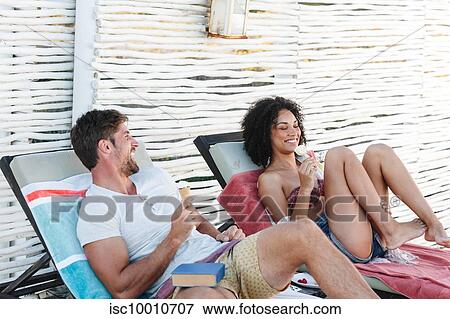 Couple talking and enjoying ice cream cone on deckchairs View Large Photo Image Stock Photo - Couple talking and enjoying ice cream cone on deckchairs. Fotosearch